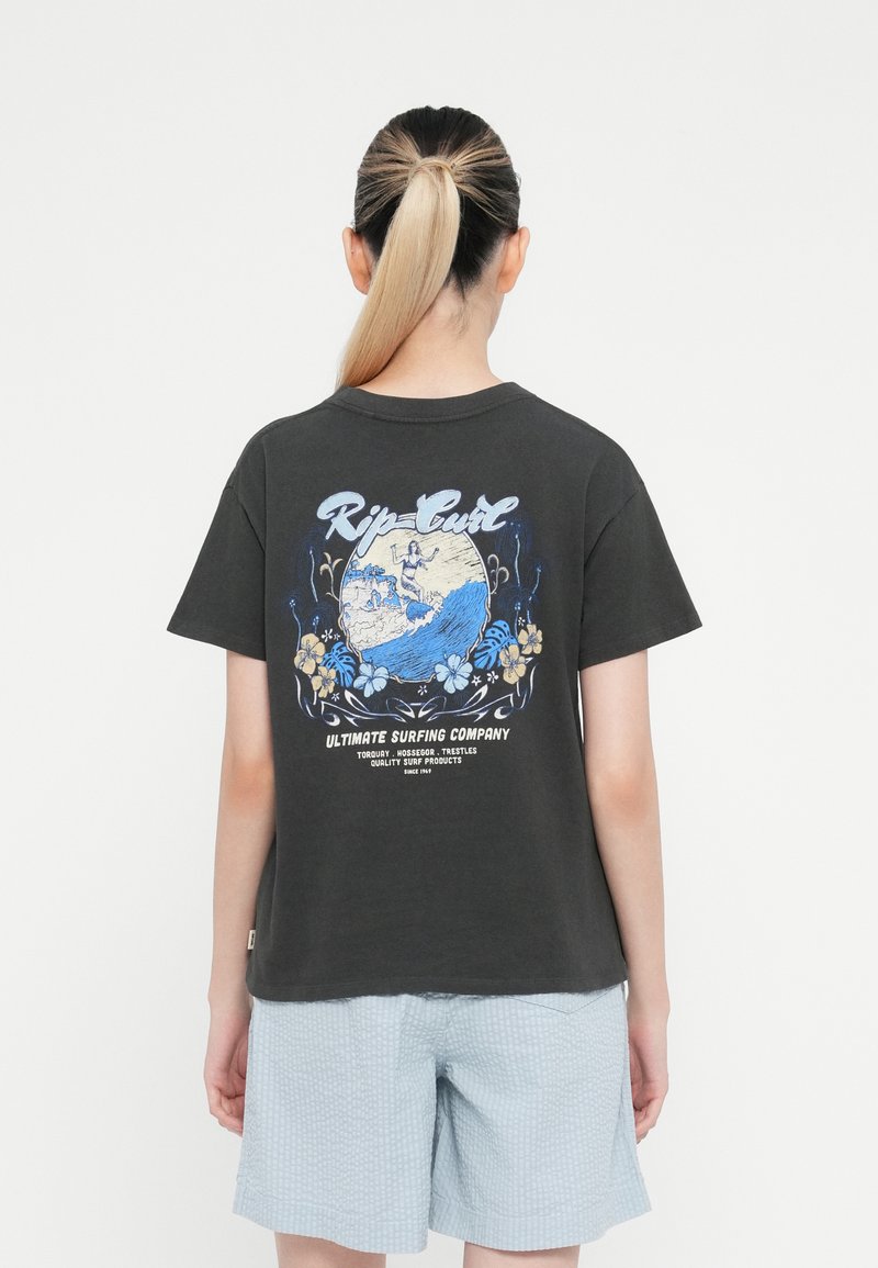 Črna bombažna majica s pisanimi grafičnimi valovi, logotipom "Rip Curl" in cvetličnimi detajli na hrbtni strani. V kombinaciji z svetlo modrimi patterned kratkimi hlačami.
