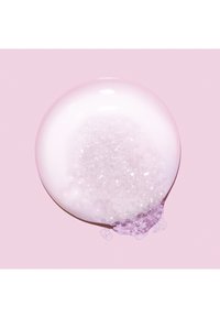 Bulle ronde et translucide avec un intérieur blanc et violet clair, présentant de petites bulles et une texture lisse sur un fond rose.
