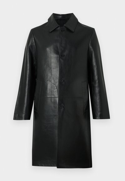 Must nahktest põlveni ulatuv nahkne mantel, millel on pikad varrukad, teravate nurkadega krae, ees nupud ja küljetaskud, taustaks hele ühtlane pind.