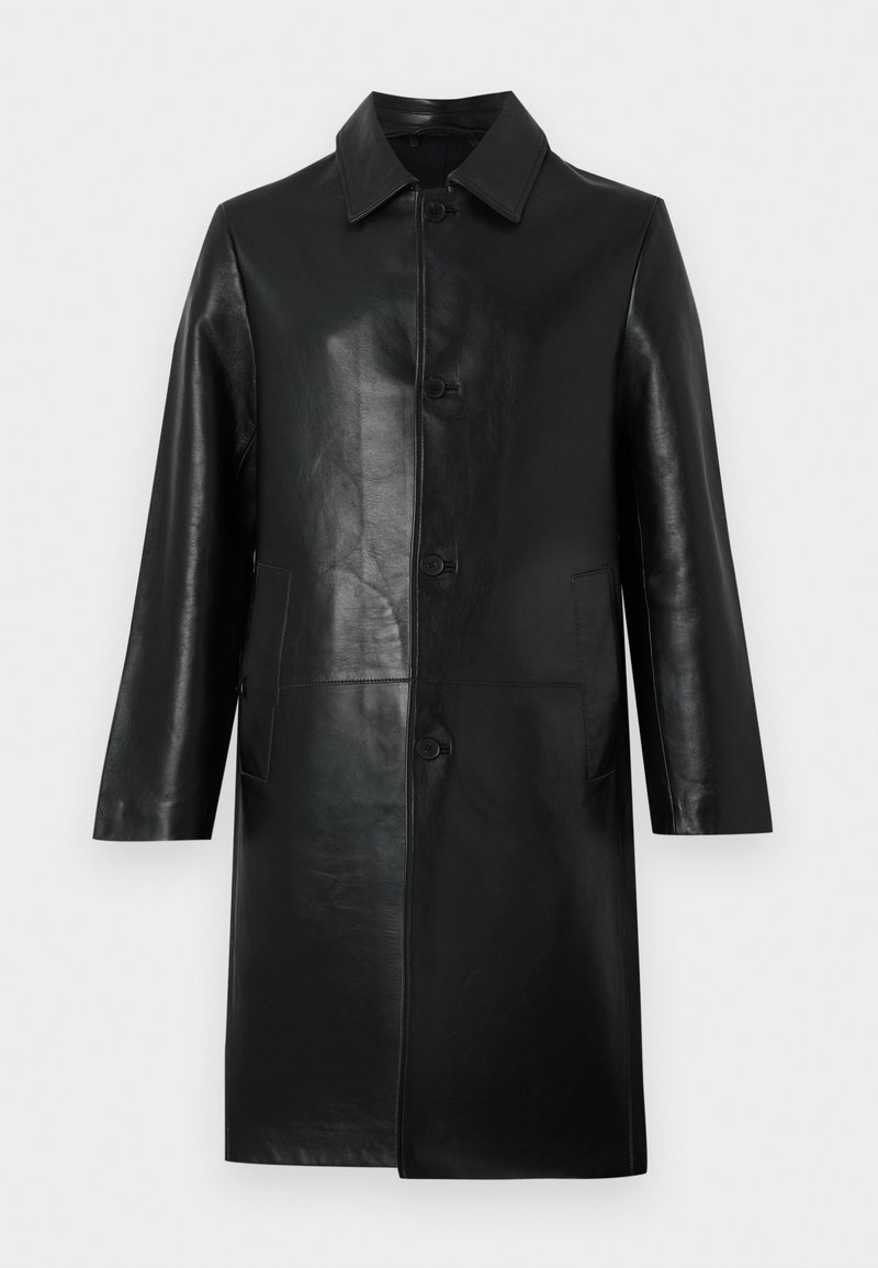 Manteau en cuir noir longueur genoux avec manches longues, col pointu, boutons sur le devant et poches latérales sur un fond clair uni.