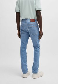 Ljust blå denimjeans med rak passform, med en brun läderlapp på baksidan av midjan och två bakfickor. Tillverkade av bomull.