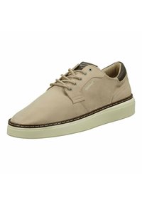 Baskets en toile beige avec des accents en cuir marron, bout rond et semelle en caoutchouc texturé beige. Elles présentent des lacets et un discret détail de couture.