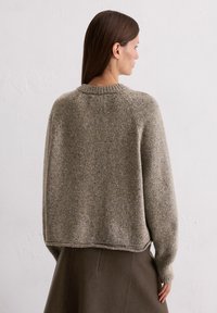 Grauer Strickpullover mit rundem Ausschnitt, überschnittenen Schultern und gerippten Bündchen. Hat ein strukturiertes, leicht meliertes Finish.