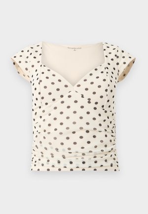 Κορυφή γυναικεία με κοντά μανίκια σε κρεμ απόχρωση, με μαύρες πουά, λαιμόκοψη καρδιά και μαζεμένες πτυχές στα πλαϊνά.