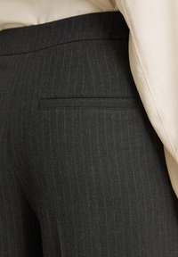 Grijs gestreepte broek met een rechte snit, gemaakt van een gestructureerde stof. Heeft een paspelzak aan de achterkant en een gladde tailleband.