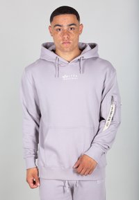 Svetlo šedá mikina s kapucňou vyrobená z mäkkej látky, s prednou vreckom, kapucňou na šnúrku a s logom na hrudi a na rukáve.