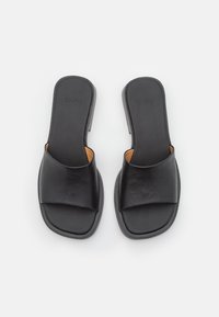 Pair of black slide sandals with wide leather straps and square-toe design, positioned side by side on a white background.