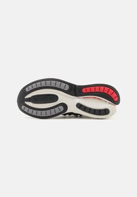 Fekete-fehér sneaker talp piros és szürke gumis kiemelésekkel. Strukturált felülettel és jellegzetes bordázott mintázattal rendelkezik a tapadásért.