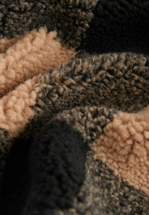 Coperta in pile di colore marrone scuro, beige chiaro e nero. Texture morbida con una finitura soffice e macchie di colore variabili che creano un aspetto accogliente.