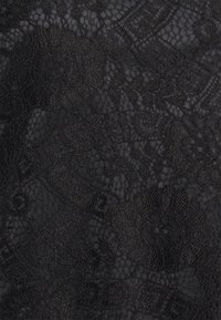 Svart spets tyg med blommigt och bladmönster, som visar delikat, intrikat sömnad och halvtransparent nätbakgrund.