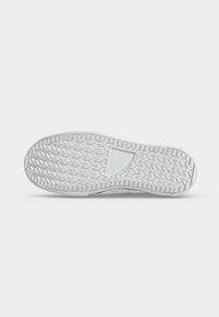 Semelle de basket blanche avec motif chevrons en zigzag et logo Converse au centre, vue du dessous sur fond uni.