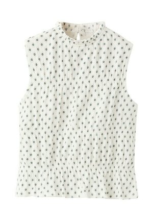 Blouse blanche sans manches avec petit motif de pois bleus circulaires, taille élastique froncée et fermeture à bouton à goutte à l'arrière de l'encolure.