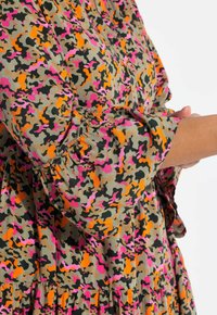 Patroon jurk met een multicolor camouflage ontwerp in roze, oranje en zwart. Gemaakt van lichtgewicht stof met gathered mouwen.