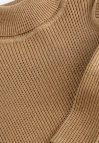 Braun geripptes Strickgewebe mit strukturierten Oberfläche, versehen mit einem hohen Kragen und glatten Kanten, was ein weiches und flexibles Design schafft.