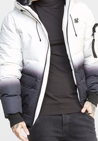 Puchowa kurtka z białym do czarnego ombre, zamek błyskawiczny, dwie kieszenie z przodu i logo marki na klatce piersiowej.