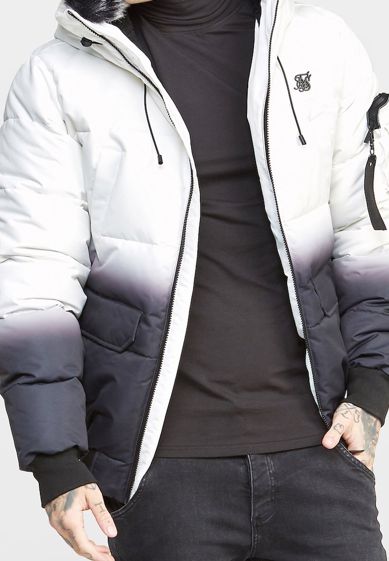 Puchowa kurtka z białym do czarnego ombre, zamek błyskawiczny, dwie kieszenie z przodu i logo marki na klatce piersiowej.