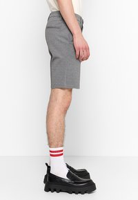 Gray fabric shorts with a tailored fit, featuring a smooth texture and back pockets, paired with black loafers and white striped socks.