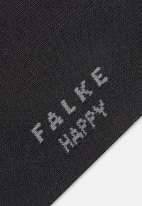 Μαύρο ύφασμα με πλεκτή υφή που φέρει λευκό κείμενο με τη φράση "FLAKE HAPPY" διαγώνια στην επιφάνεια.