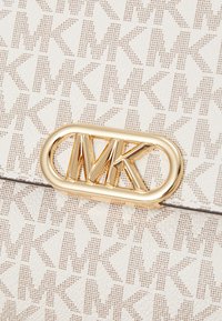 Sac à main texturé blanc avec un détail en matériel doré portant le logo MK, et un motif d'initiales MK stylisées sur la surface.
