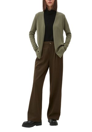 Olijfgroene cardigan over een zwarte coltrui, gecombineerd met wijde bruine broeken en zwarte chunky laarzen; zachte textuur en ontspannen pasvorm.