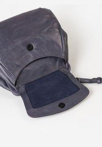 Borsa in pelle viola con finitura liscia, dotata di chiusura a soffietto e interno in suede scuro. Include un pulsante a scatto e una tracolla.