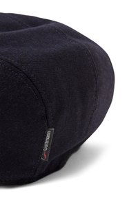 Ciemnoniebieska wełniana czapka typu flat cap z widocznymi przeszyciami i małą czarną etykietą z napisem "Göttmann" na białym tle.