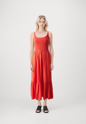 Robe maxi rouge avec un corsage ajusté et froncé, des bretelles larges et une jupe à volants. Fabriquée en tissu doux, elle offre une coupe décontractée et une texture lisse.