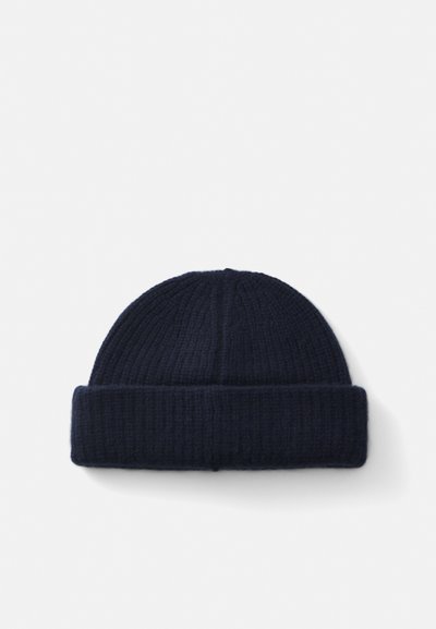 Navy knitted beanie made from textured fabric, featuring a rolled cuff and vertical ribbing for warmth and comfort.