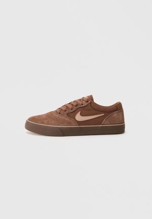Brown suede and fabric low-top Nike sneaker with laces and beige swoosh logo on side, against plain light background.