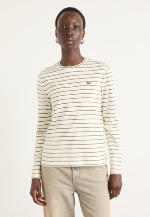 Long-sleeve shirt with white base and yellow stripes. Features a round neckline and emblem on the chest. Cotton fabric with a smooth texture.