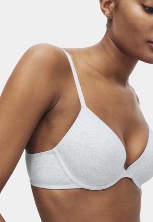 Sujeción gris claro, acolchada, con tirantes finos ajustables y una textura suave. Presenta un diseño sin costuras y detalles de costura sutiles.