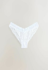 Valkoinen pitsinen pöksy, jossa on aaltoilevat reunat, ja jossa on kukkakuvioita sekä joustava vyötärö. Kankaan ilme on herkkä ja kevyt.