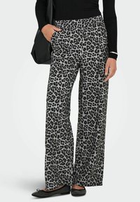 Pantaloni a gamba larga con stampa leopardata in grigio e nero, dotati di una vita elastica e tasche laterali, abbinati a ballerine nere decorate.