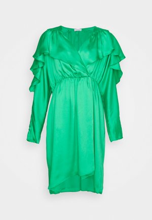 Zelena satenska haljina s dugim rukavima, dubokim V-izrezom i lepršavim volanima. Elastični pojas i asimetrična donja ivica ističu uočljivo drapiranje.