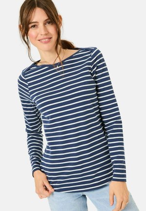 Marineblaues Langarmshirt mit weißen horizontalen Streifen, rundem Ausschnitt und weichem, dehnbarem Material; kombiniert mit hellblauen Jeans.