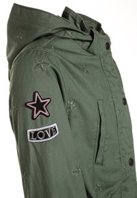 Veste à capuche vert olive avec broderie d'étoiles, dotée d'un patch en forme d'étoile rose et d'un patch noir "LOVE", conçue avec une fermeture à boutons.