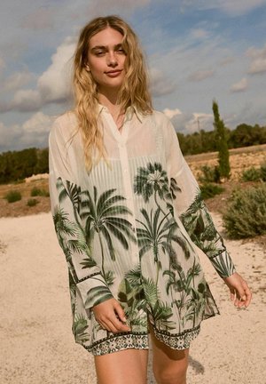 Lichte, doorschijnende knoopsluiting shirt met een palmbladerenprint in groen op een witte achtergrond, met een patroon aan de onderkant en lange mouwen.
