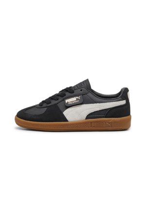 Czarno-białe sneakersy Puma Palermo z gumową podeszwą, czarnymi sznurowadłami i logo Puma na boku i podeszwie, widoczne od zewnętrznej strony.