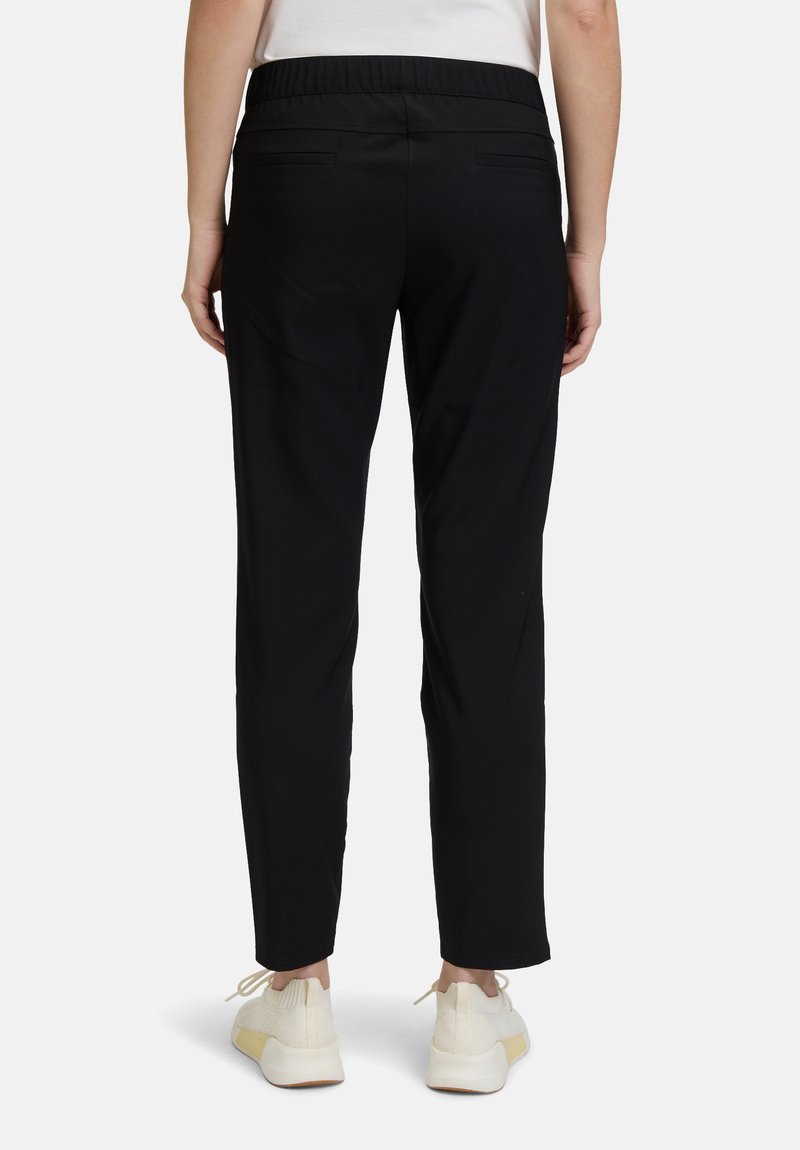 Černé slim-fit kalhoty s elastickým pasem, dvěma zadními kapsami a hladkým, lehkým materiálem. Spárováno s bílými botami.