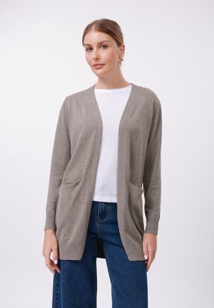 Light gray knitted cardigan with open front, two front pockets, and ribbed cuffs. Worn over a white top and paired with blue jeans.