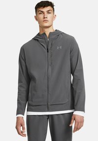 Grå zip-up hættejakke i letvægtsstof, justerbar hætte og Under Armour-logo. Har en glat overflade og afslappet pasform.