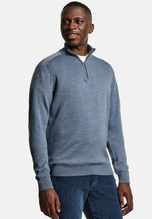 Pull à col zip bleu en tissu tricoté doux, doté d'une coupe structurée, de poignets côtelés et d'une surface texturée. Assorti à un pantalon bleu foncé.