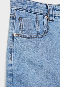 Jeans in denim azzurro chiaro con una finitura testurizzata, dotati di una piccola tasca frontale, hardware in rame e cuciture marroni a contrasto.