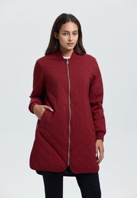 Gequilted bordeaux jacket met een rits aan de voorkant, ronde kraag, lange mouwen en zijzakken; gladde textuur en knielange ontwerp.