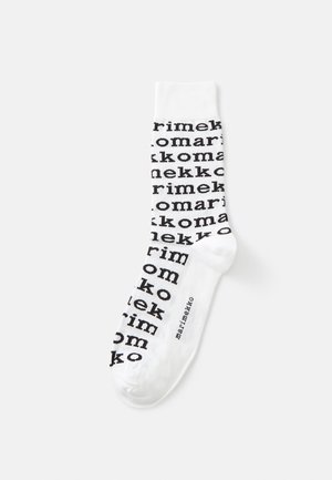 Valkoiset sukat, joissa on toistuva musta teksti, joka spellaa "marimekko" ja "komarikko". Pehmeä kangas, jossa on sileä rakenne.