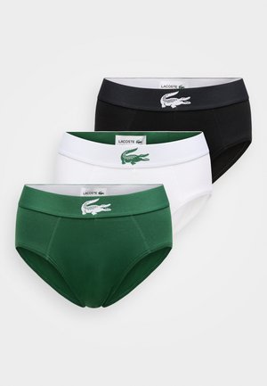 Tre paia di slip da uomo in cotone nero, bianco e verde, ciascuno con una fascia in vita a contrasto e il logo Lacoste.