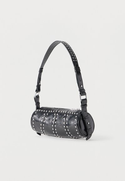 Μαύρη κυλινδρική τσάντα χειρός με ρυθμιζόμενο λουρί και ασημί διακοσμητικά καρφιά, παρουσιασμένη σε απλό ανοιχτό φόντο.