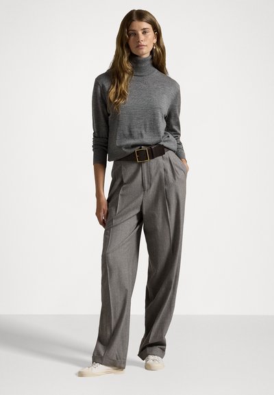 Grå høyhalset genser laget av myk strikket stoff, kombinert med lysegrå høytlivsbukser, med et brunt belte og hvite sneakers.
