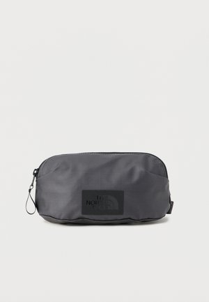Compact black nylon pouch with zipper and The North Face logo patch on the front, shown against a white background.