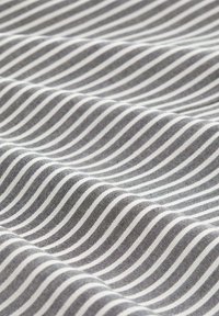Tissu gris avec des rayures ondulées alternées en blanc et gris clair. La texture semble lisse avec une finition semblable à celle du coton.